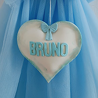 Particolare del nome "Bruno" scritto in stamaptello azzurro su pendente a forma di cuore.